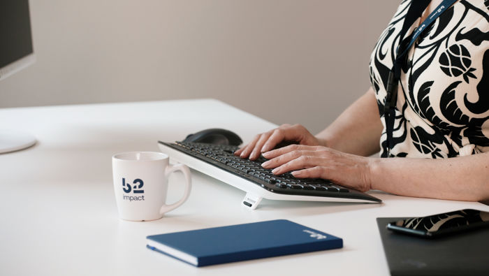 Woman sitting behind a desk with books on it working on a PC